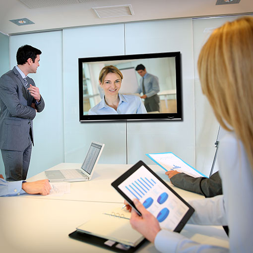 Business Peaople havinga a meeting with one colleague joining remotely via big screen